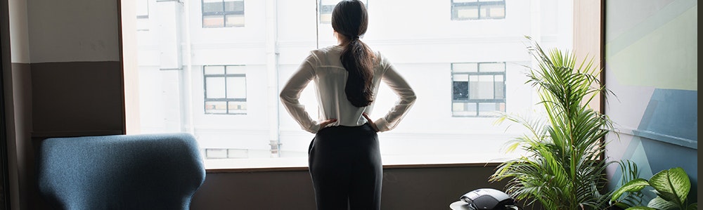 female-executive-looks-out-modern-office-window-jpg